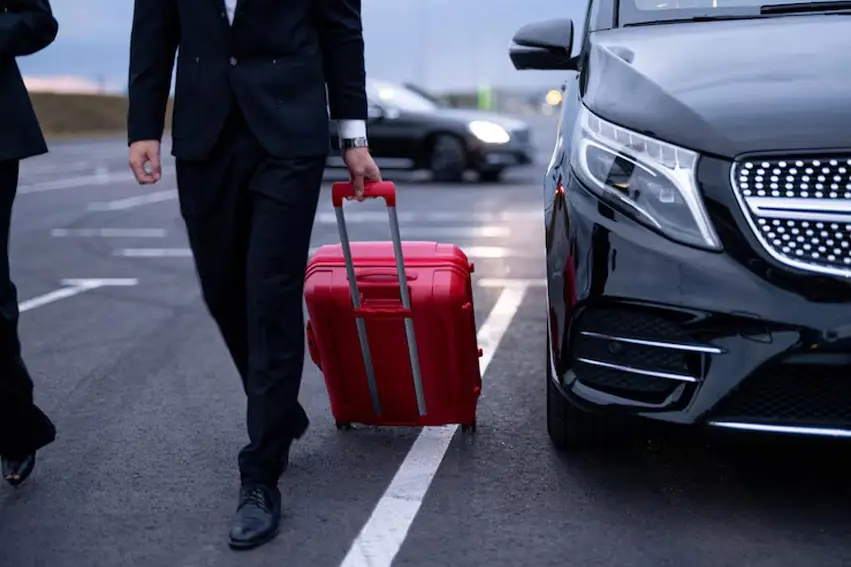 a man in a suit pulling a red suitcase